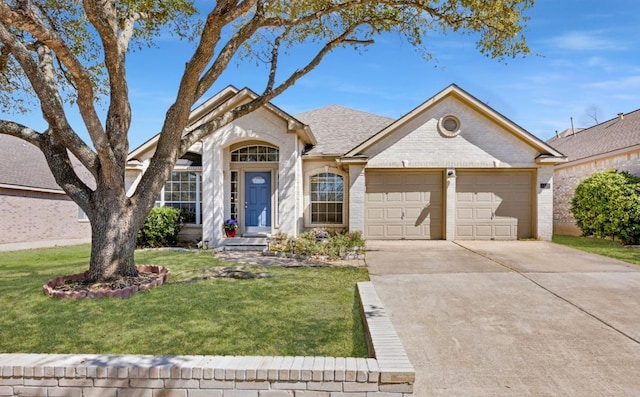 view of front of home with a front yard, an attached garage, a shingled roof, concrete driveway, and brick siding