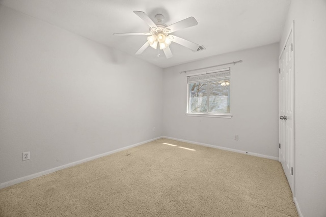 carpeted empty room with visible vents, baseboards, and a ceiling fan