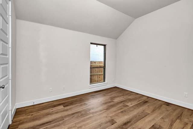 unfurnished room featuring vaulted ceiling, baseboards, and wood finished floors