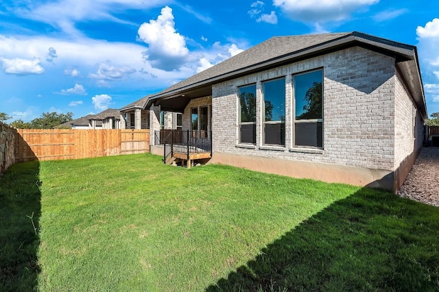 back of property with brick siding, fence, and a lawn