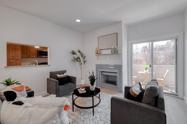 living room featuring recessed lighting, light wood-type flooring, baseboards, and a tile fireplace