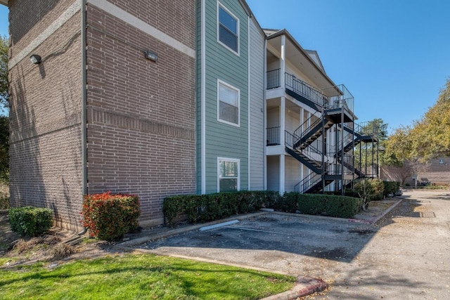 view of home's exterior with brick siding, uncovered parking, and stairs