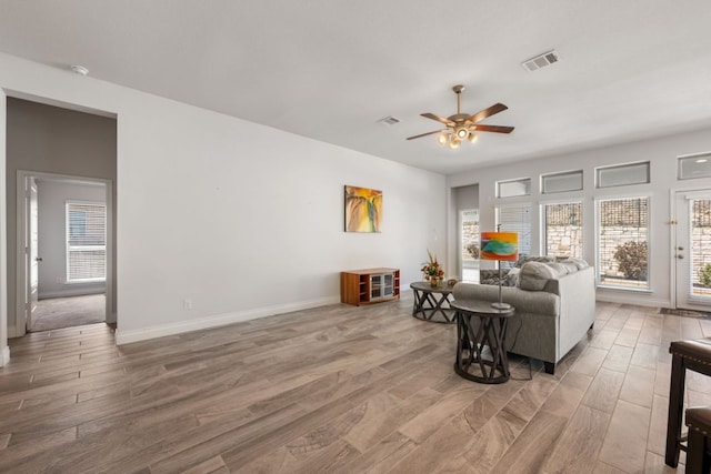 living room with wood finished floors, a ceiling fan, visible vents, and baseboards