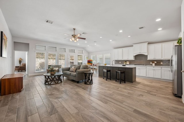 living area featuring a wealth of natural light, visible vents, and a ceiling fan