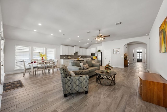 living room with light wood finished floors, lofted ceiling, recessed lighting, arched walkways, and a ceiling fan