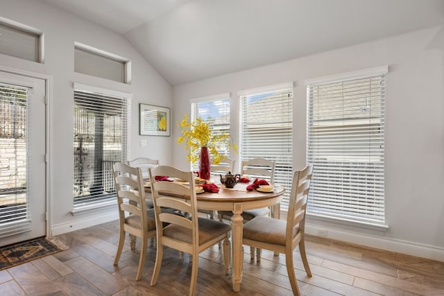 dining room featuring baseboards, wood finished floors, and vaulted ceiling