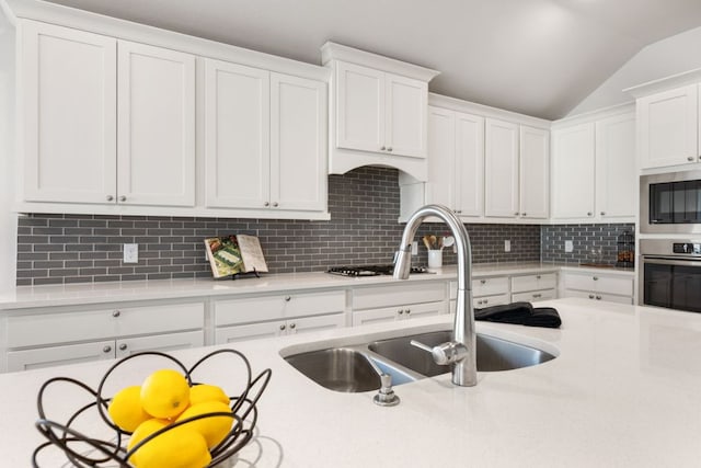 kitchen with a sink, appliances with stainless steel finishes, white cabinets, and light countertops