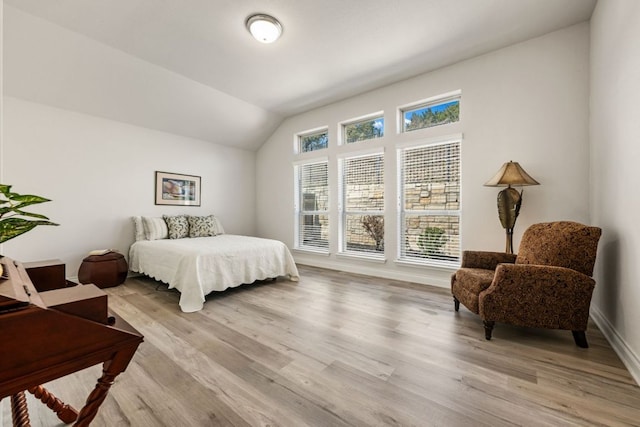 bedroom featuring lofted ceiling, baseboards, and light wood finished floors