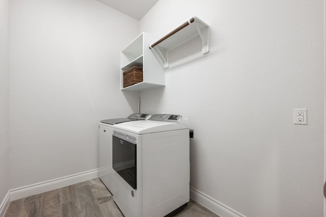 clothes washing area with laundry area, washer and dryer, and baseboards