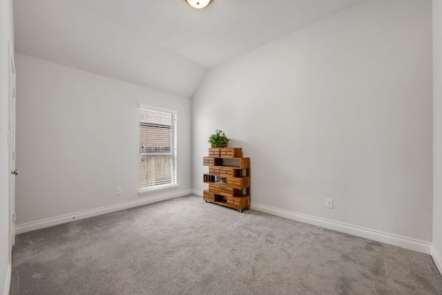 unfurnished room with vaulted ceiling, carpet flooring, and baseboards