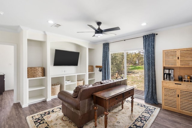 living area with wood finished floors, baseboards, visible vents, ceiling fan, and crown molding