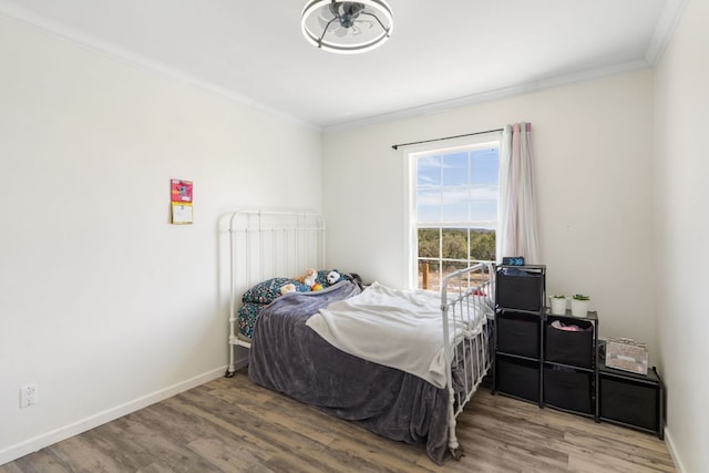 bedroom with crown molding, baseboards, and wood finished floors