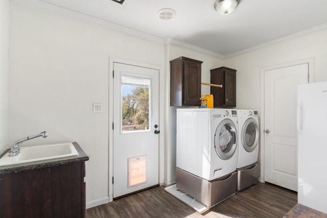 laundry area featuring dark wood-style floors, cabinet space, a sink, crown molding, and washing machine and dryer