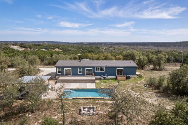 rear view of house with an outdoor pool and a deck