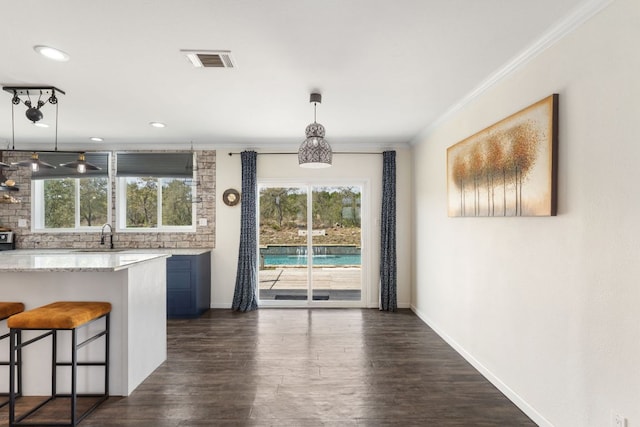 kitchen with visible vents, ornamental molding, plenty of natural light, backsplash, and a breakfast bar area