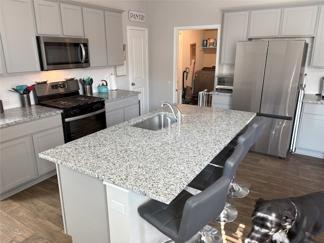 kitchen featuring a sink, decorative backsplash, gray cabinets, and stainless steel appliances