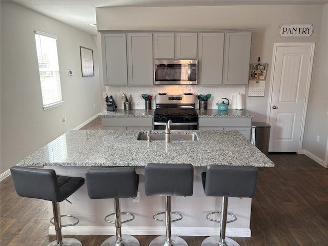 kitchen featuring a sink, backsplash, appliances with stainless steel finishes, and gray cabinetry