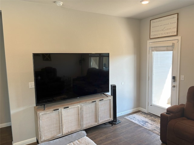 living area with baseboards and dark wood-type flooring