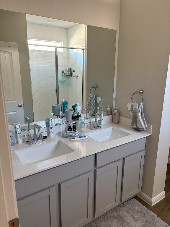 full bath with a sink, double vanity, and a shower stall