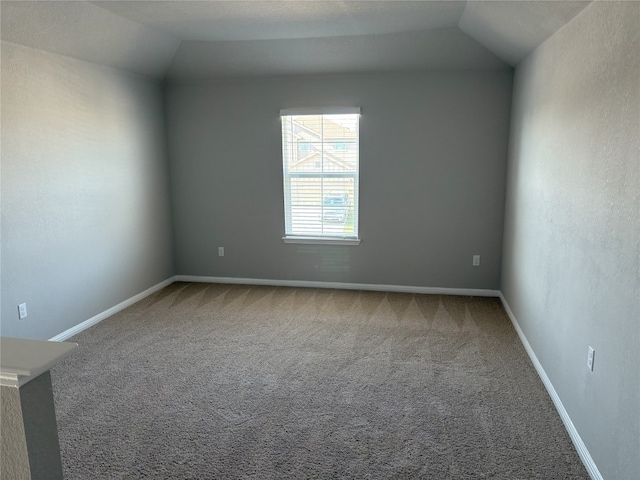 spare room featuring vaulted ceiling, carpet, and baseboards