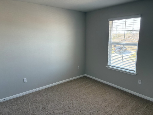 unfurnished room with plenty of natural light, baseboards, and carpet floors