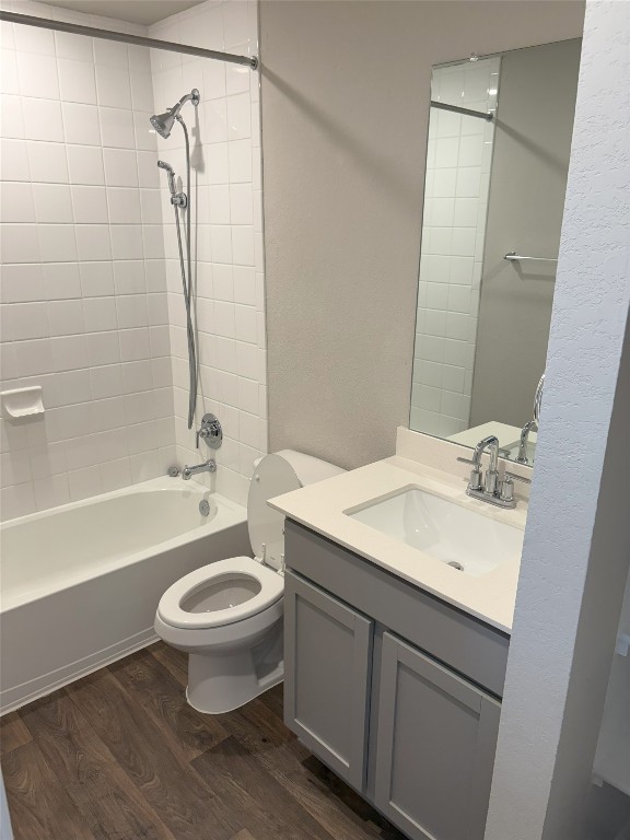 full bath featuring shower / bathing tub combination, toilet, wood finished floors, and vanity