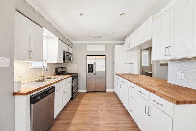 kitchen with visible vents, butcher block countertops, a sink, appliances with stainless steel finishes, and crown molding