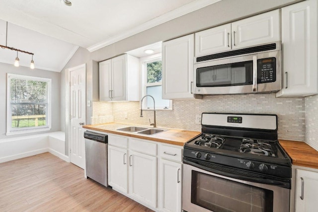 kitchen with crown molding, butcher block countertops, stainless steel appliances, white cabinetry, and a sink