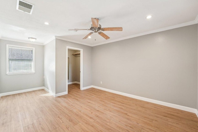 empty room featuring light wood-style floors, visible vents, crown molding, and baseboards