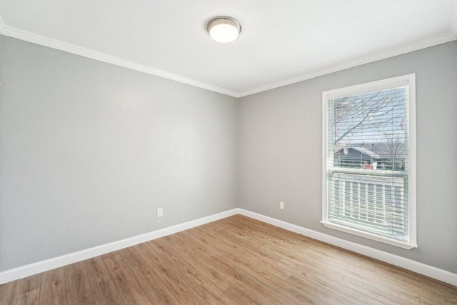 spare room featuring crown molding, light wood-type flooring, and baseboards