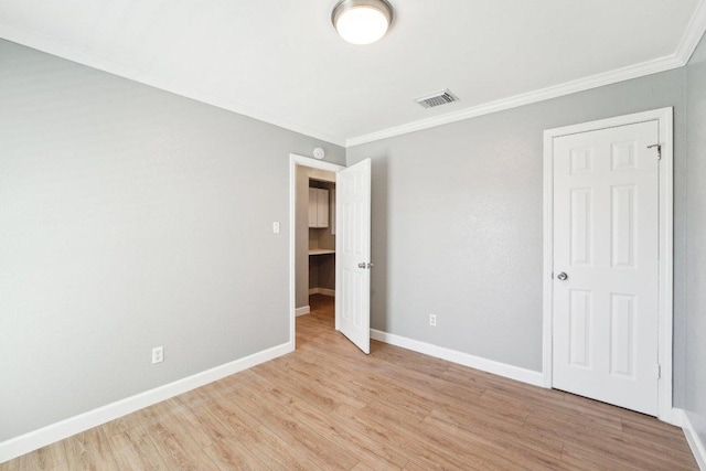 unfurnished bedroom featuring light wood-type flooring, baseboards, visible vents, and crown molding