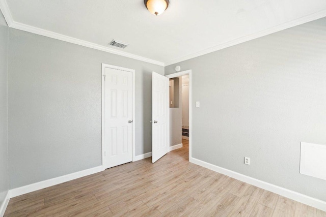 spare room with visible vents, baseboards, light wood-style floors, and crown molding