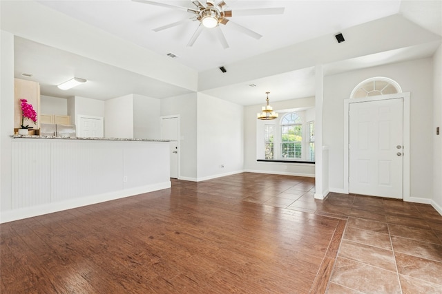 unfurnished living room with visible vents, baseboards, wood finished floors, and ceiling fan with notable chandelier