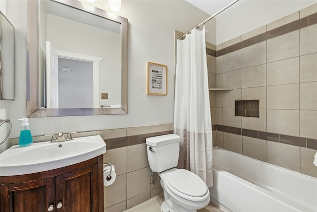 full bath featuring vanity, a wainscoted wall, shower / tub combo, tile walls, and toilet