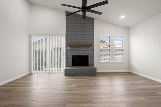 unfurnished living room with wood finished floors, a fireplace, baseboards, ceiling fan, and vaulted ceiling