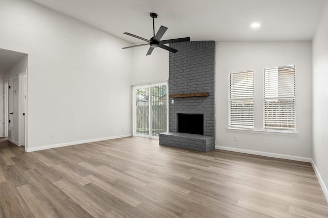 unfurnished living room featuring light wood-style flooring, a brick fireplace, baseboards, and ceiling fan