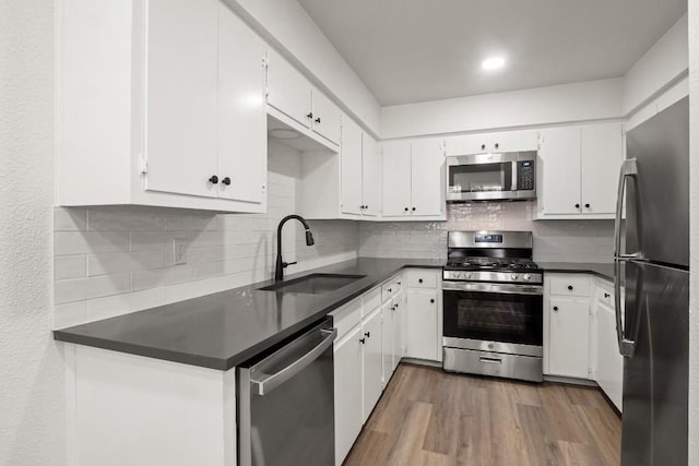 kitchen with dark countertops, wood finished floors, appliances with stainless steel finishes, and a sink