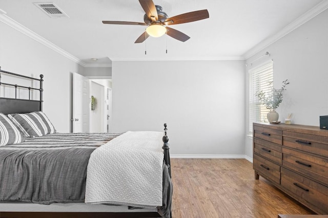 bedroom featuring crown molding, wood finished floors, baseboards, and visible vents