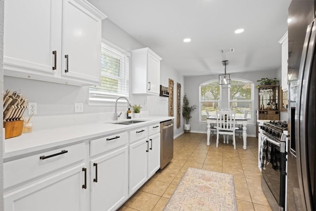 kitchen featuring light countertops, light tile patterned floors, appliances with stainless steel finishes, white cabinetry, and a sink