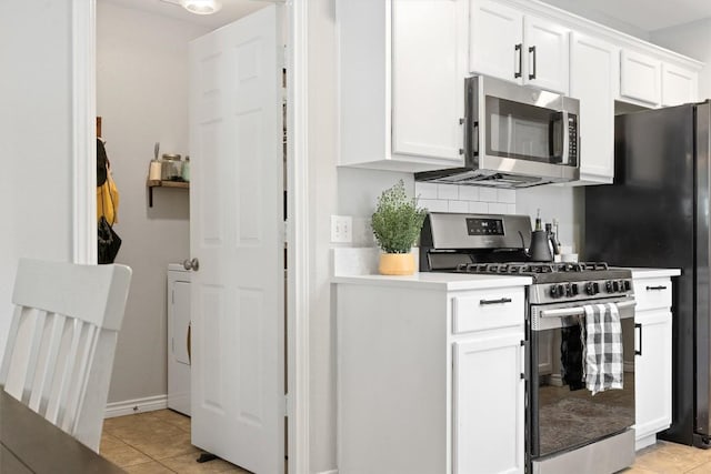 kitchen featuring light tile patterned floors, light countertops, appliances with stainless steel finishes, white cabinetry, and tasteful backsplash