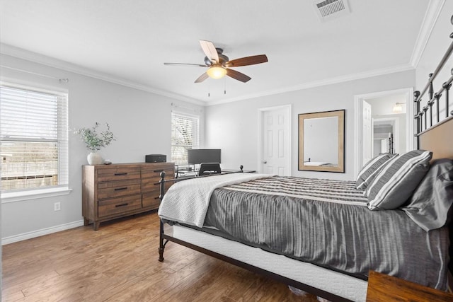 bedroom featuring a ceiling fan, wood finished floors, visible vents, baseboards, and crown molding