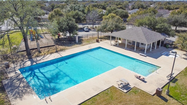 community pool featuring a patio area, a lawn, and fence