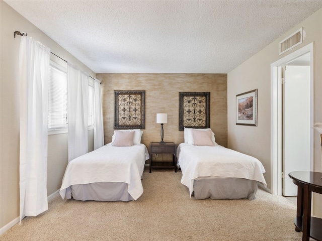 carpeted bedroom featuring baseboards, visible vents, and a textured ceiling