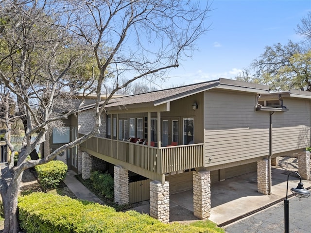 exterior space featuring an attached garage, driveway, and a shingled roof