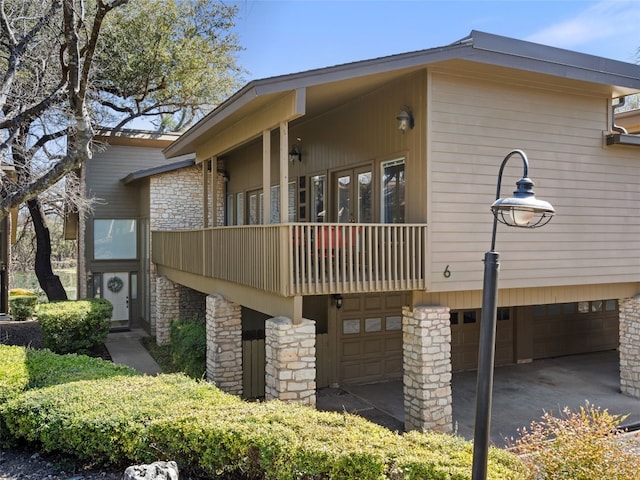 view of property exterior featuring stone siding, a balcony, and a garage