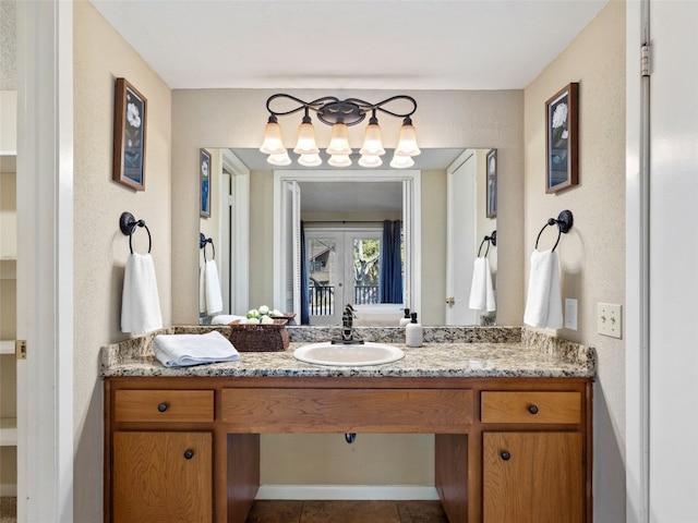 bathroom featuring a chandelier, tile patterned floors, vanity, and a textured wall