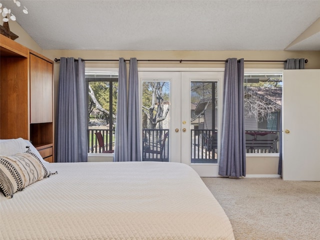 bedroom featuring access to exterior, vaulted ceiling, carpet floors, french doors, and a textured ceiling