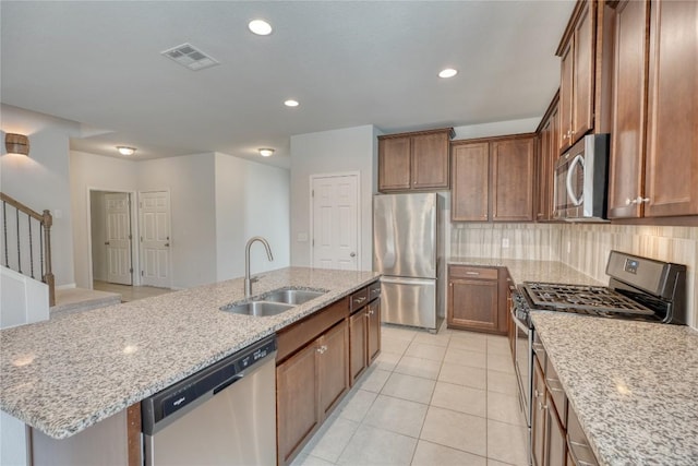 183 Concho Creek Loop, Leander, TX 78641 - kitchen featuring appliances with stainless steel finishes, decorative backsplash, light stone counters, light tile patterned floors, and recessed lighting