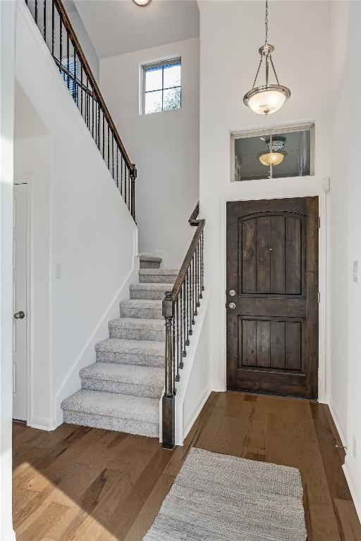 entryway featuring stairway, baseboards, a high ceiling, and wood finished floors