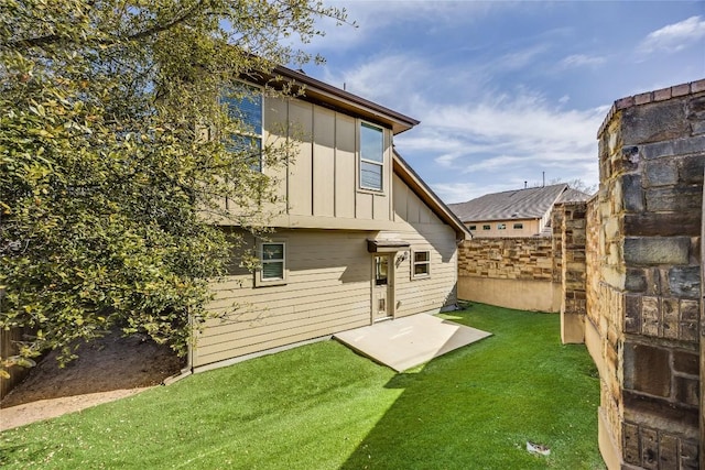 rear view of property with a lawn, board and batten siding, and fence